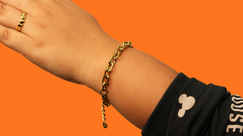 18k gold plated bracelet on a wrist against an orange background elazo