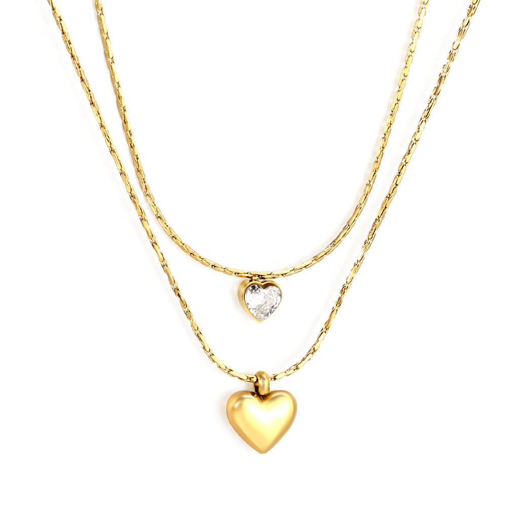 Two gold heart-shaped pendants on gold chains against a white background