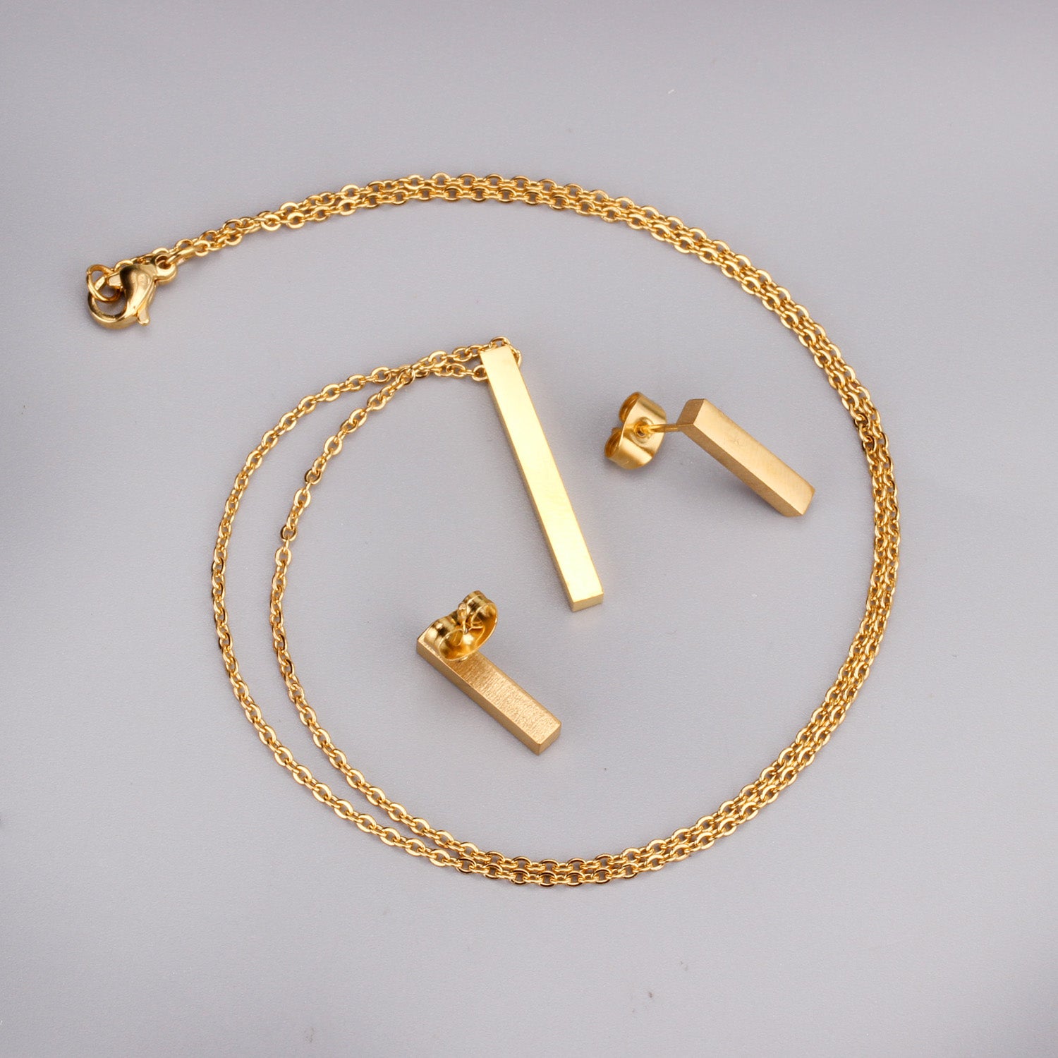 Gold necklace and earrings on a gray background